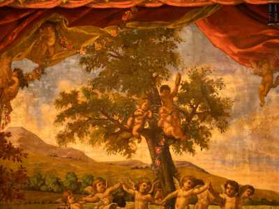 Al centro della scena dei graziosi angioletti ballano in cerchio attorno a un albero su un paesaggio lacustre con delle colline sullo sfondo